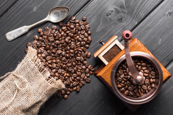 top view of roasted coffee beans in sack, coffee grinder and spoon on table